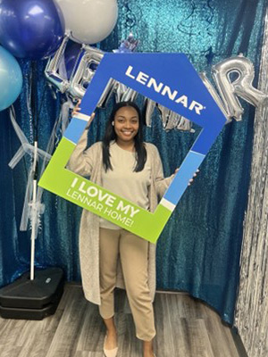 Moesha Black take a photo hold a Lennar frame home to celebrate her purchase.