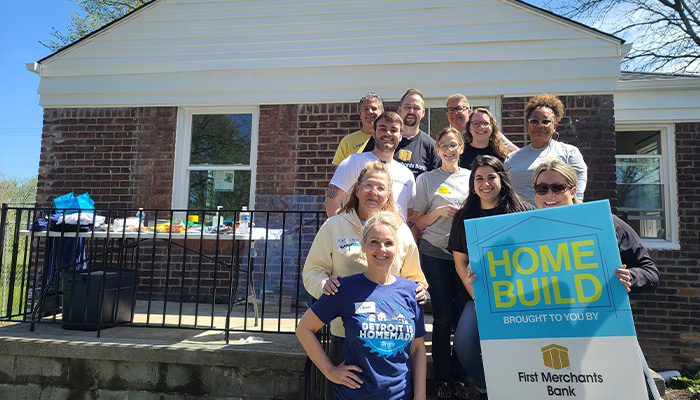 First Merchants Team Members posing in front of the home with a sign - Horizonal..