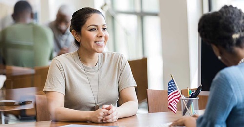 Veteran-Apprenticeship-Checking1200x630 Female soldier sitting and talking with a banker.