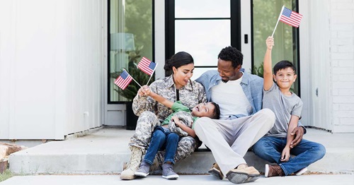 Veteran-Apprenticeship-Mortgage1200x630 Diverse military family sitting in front of their new home.