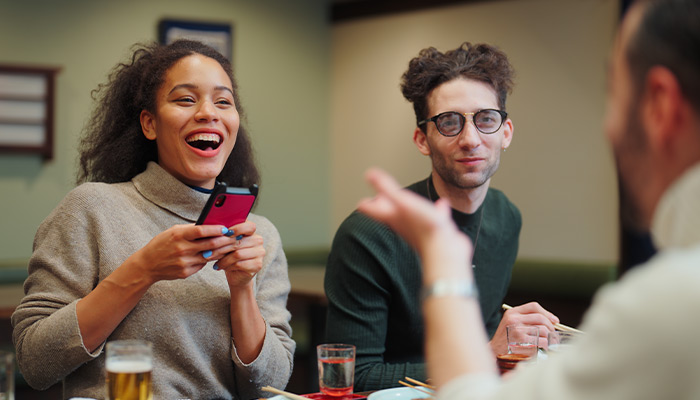 Diverse friends talking over dinner and transferring money to split the bill